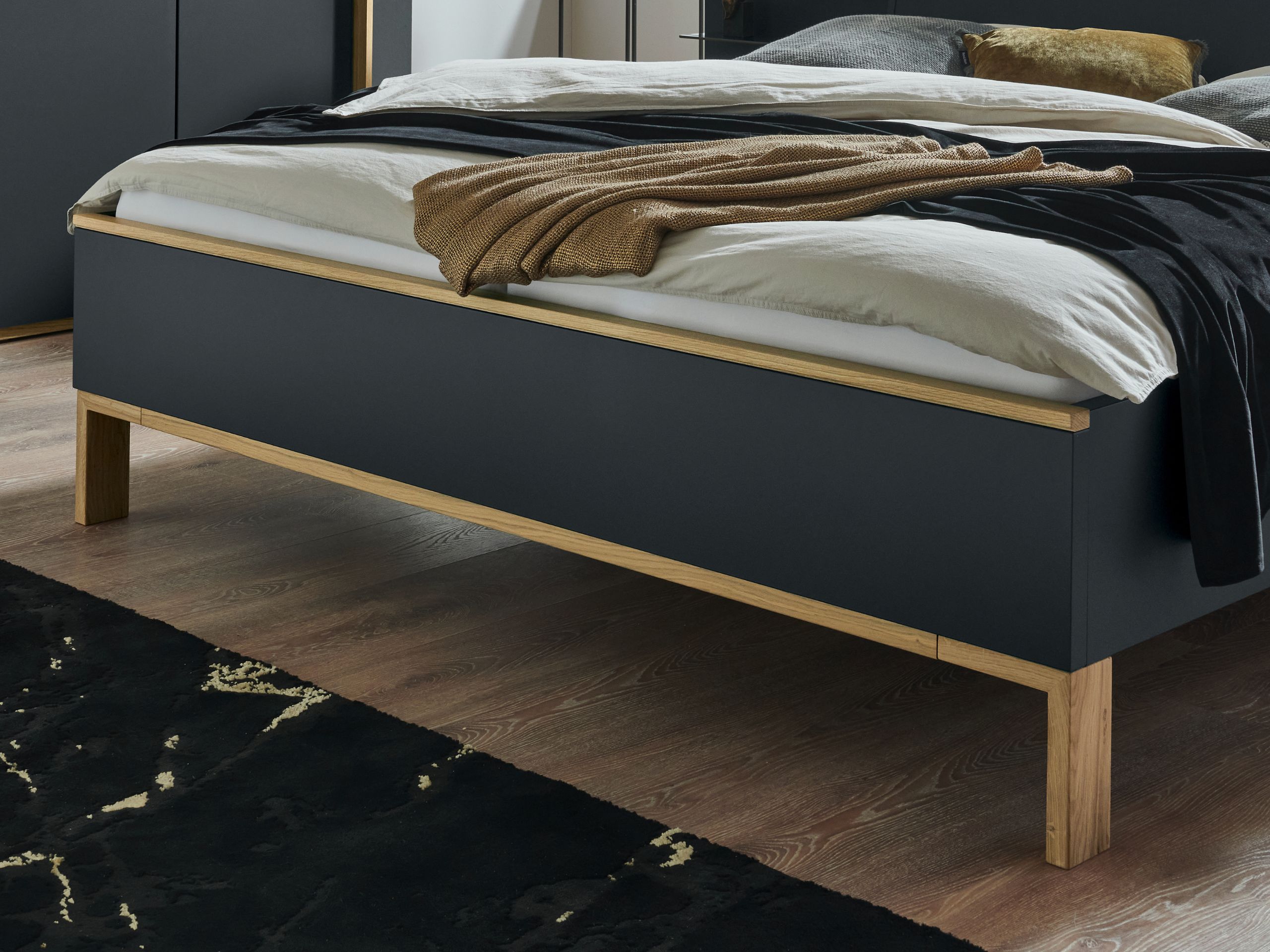 Bett Cuneo mit Winkelfüßenn in Lack Basalt mit Fokus auf das Fußteil.