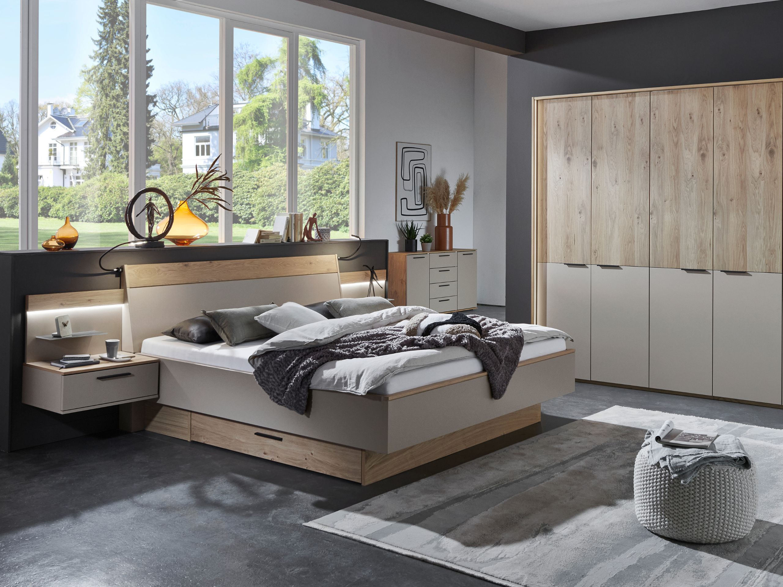 Schlafzimmerkombination Cuneo mit sechstürigem Kleiderschrank, Doppelbett mit schwebendem Fußteil und Hängekonsolen mit Panelaufsatz und Glasboden, sowie indirekter Beleuchtung.