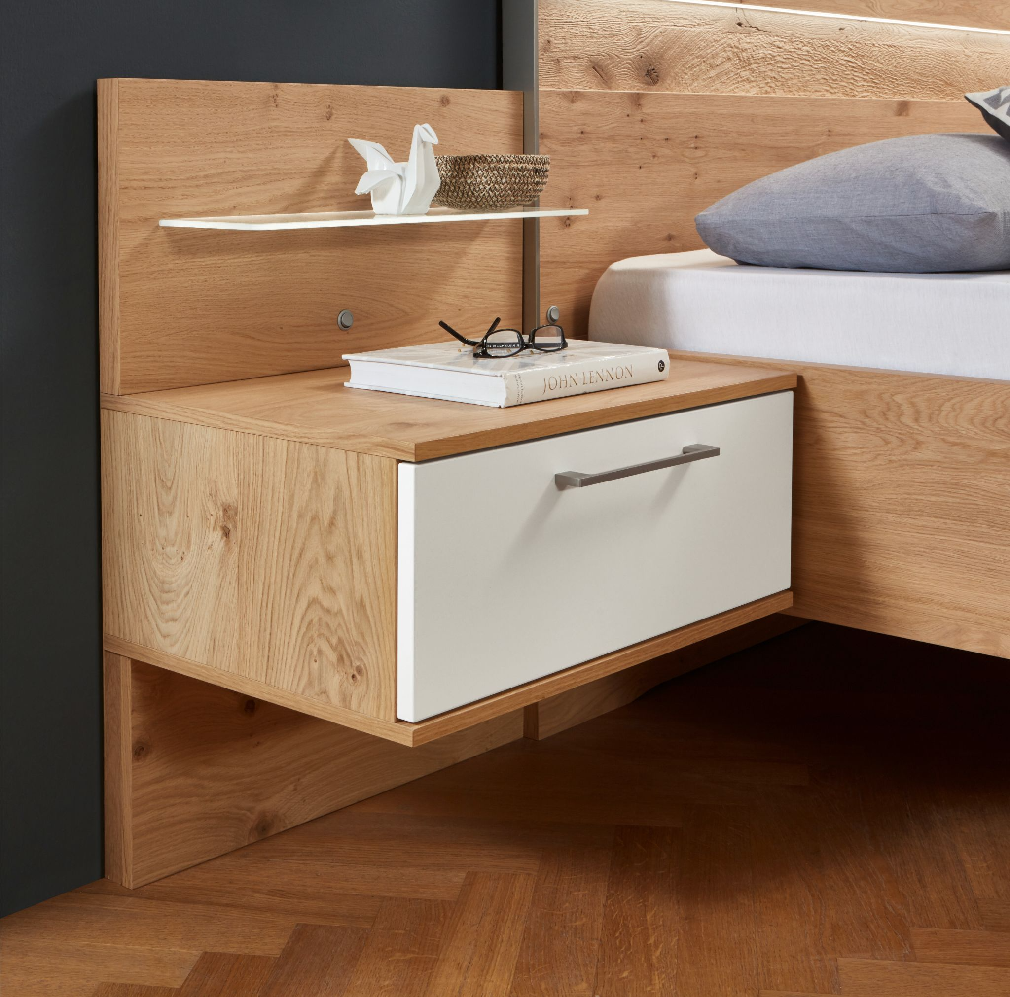 Hier sieht man ein Nachttischelement aus Holz (Kernbuche) mit einer weißen Schubladenfront. Es dient als Beispiel für Zubehörmöglichkeiten. 